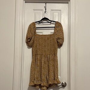 Yellow romper with white floral detail and smocked bodice and cap sleeves